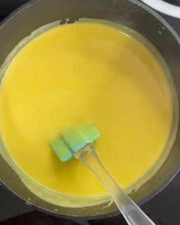 Una ciotola di liquido giallo con un cucchiaio dentro.