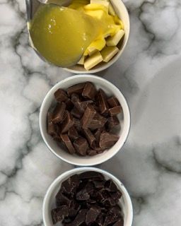 Tre ciotole di cioccolato, burro e salsa su un tavolo.