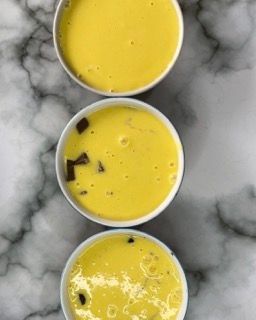 Tre ciotole di zuppa gialla sono allineate su un tavolo.