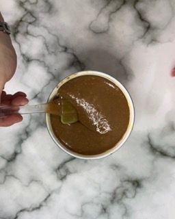 Una persona tiene un cucchiaio in una ciotola di zuppa.