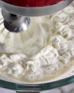 Uno sbattitore elettrico mescola la panna montata in una ciotola di vetro.