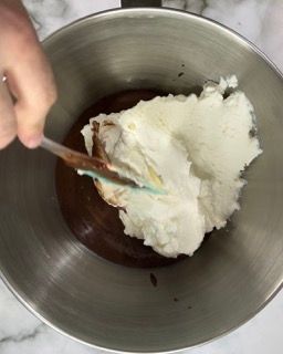 Una persona mescola una ciotola di cioccolato e panna montata con una spatola.