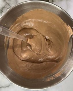 Una ciotola di glassa al cioccolato con un cucchiaio dentro.