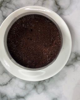 Una ciotola di budino al cioccolato è appoggiata su un tavolo di marmo.