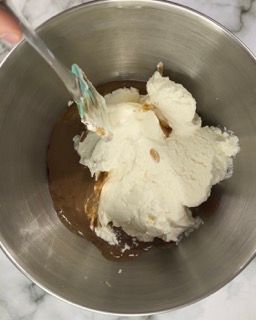 La panna montata viene versata in una ciotola di metallo con una spatola.