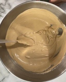 Una ciotola di liquido marrone con un cucchiaio dentro.