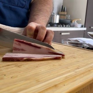 Una persona sta tagliando un pezzo di carne su un tagliere