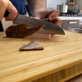 Una persona sta tagliando un pezzo di carne su un tagliere
