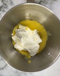 Una ciotola di metallo piena di uova e panna montata.