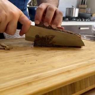 Una persona sta tagliando un pezzo di pane su un tagliere