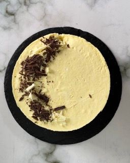 Una torta gialla con scaglie di cioccolato sopra su un piatto nero