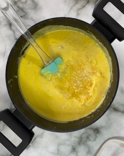 Una pentola di zuppa gialla con una spatola dentro.