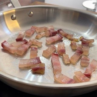 La pancetta viene cotta in una padella sul fornello.