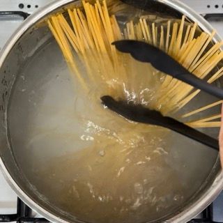Gli spaghetti vengono cotti in una pentola con le pinze