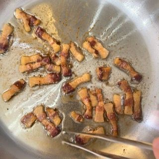 La pancetta viene cotta in una padella con le pinze