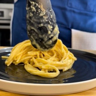 Una persona tiene una pinza sopra un piatto di spaghetti.