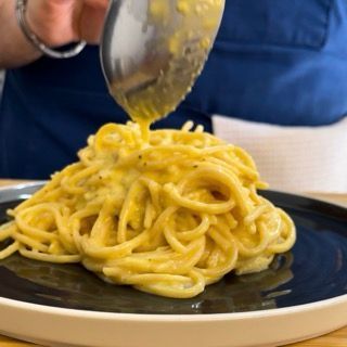 Una persona sta versando la salsa su un piatto di spaghetti