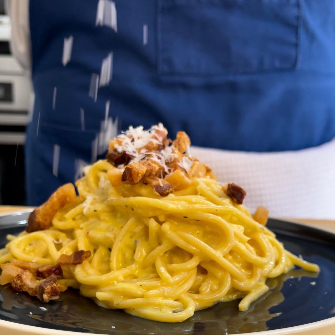 Una persona sta cospargendo il formaggio su un piatto di spaghetti