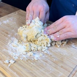 Una persona sta impastando l'impasto su un tagliere di legno