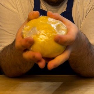 Un uomo con un grembiule tiene in mano una palla gialla