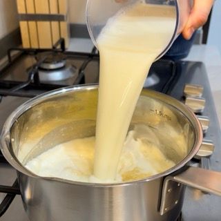 Una persona sta versando del liquido in una pentola sul fornello