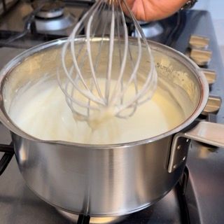 Una persona sta montando la panna in una pentola sul fornello