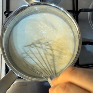 Una persona sta sbattendo una pentola di liquido su un fornello