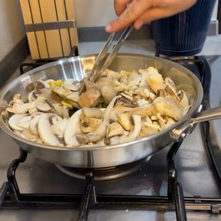 Una persona sta mescolando una padella di funghi su un fornello