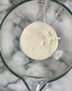 Un misurino di vetro riempito con un liquido bianco.