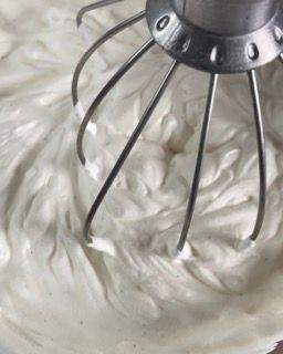 Primo piano di una frusta in una ciotola di panna montata.