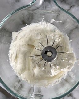 Un primo piano della panna montata in un frullatore su un tavolo.