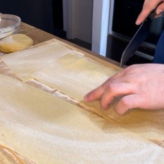 Una persona sta tagliando un pezzo di pasta su un tagliere