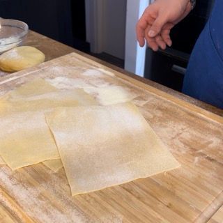 Una persona sta tagliando un pezzo di pasta su un tagliere di legno