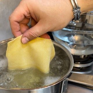 Una persona tiene un pezzo di pasta sopra una pentola di acqua bollente