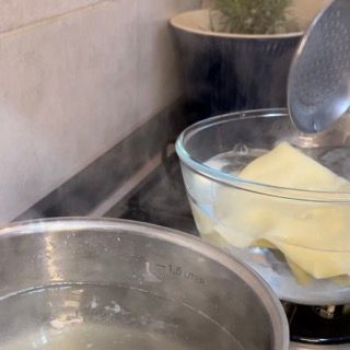Una ciotola di burro viene versata in una pentola di acqua bollente