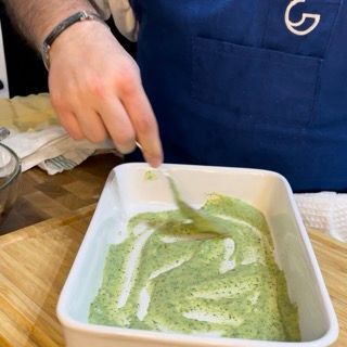 Una persona sta mescolando una salsa verde con una forchetta