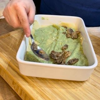 Una persona tiene un cucchiaio sopra una ciotola di cibo