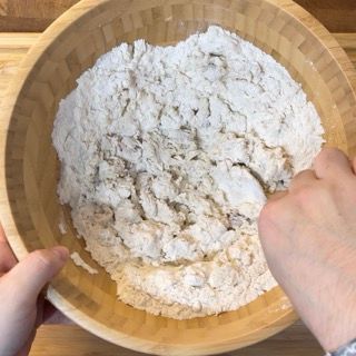 Una persona sta mescolando la farina in una ciotola di legno