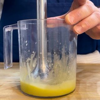 Una persona sta usando un frullatore per mescolare un liquido giallo