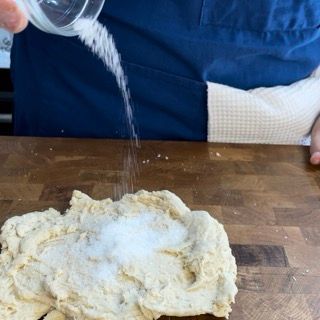 Una persona sta versando sale in un mucchio di pasta