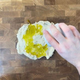 Una persona sta spalmando dell'olio su un pezzo di pasta