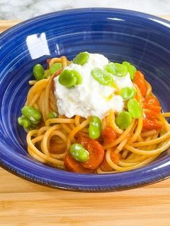 Una ciotola blu piena di spaghetti, fagioli, pomodori e ricotta.