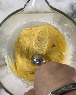 Una persona sta mescolando il gelato in una ciotola di vetro con un cucchiaio.