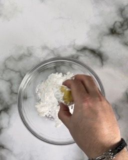 Una persona tiene in mano un pezzo di burro in una ciotola di farina.