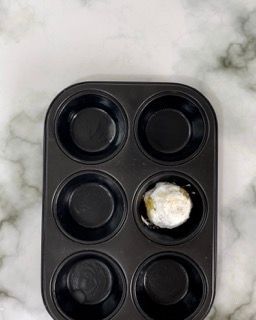 Uno stampo per muffin con quattro pirottini e una pallina al centro.