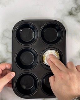 Una persona sta mettendo un muffin in uno stampo per muffin.