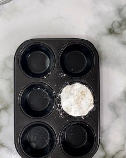 Uno stampo per muffin pieno di cupcake e zucchero a velo su un tavolo.