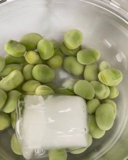 Una ciotola di fagiolini con un cubetto di ghiaccio dentro.