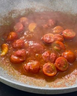 I pomodori vengono cotti in una salsa in una padella.