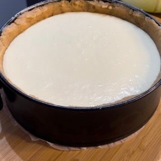 Una cheesecake in una padella è appoggiata su un tavolo di legno.